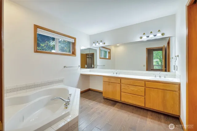 a spacious bathroom with a tub sink and mirror