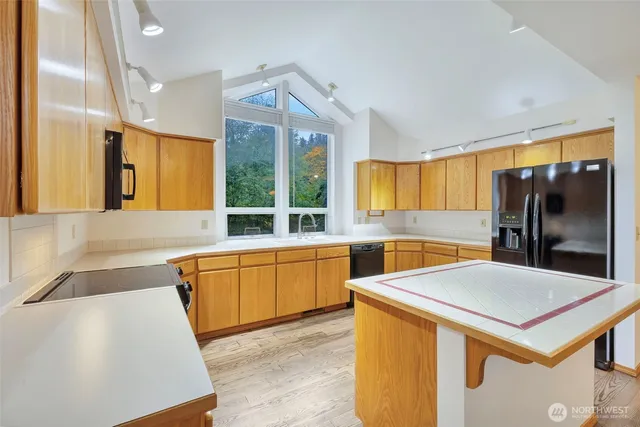 a kitchen with sink a refrigerator and wooden cabinets