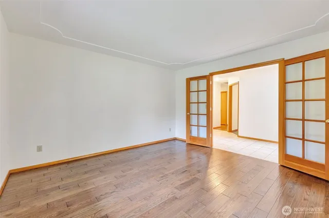 a view of an empty room with wooden floor and a window