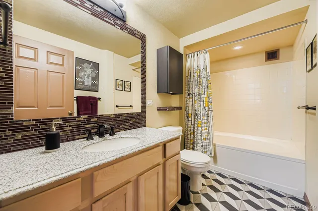 a bathroom with a granite countertop sink toilet a mirror and shower