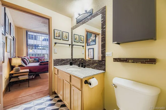 a bathroom with a granite countertop toilet sink and mirror