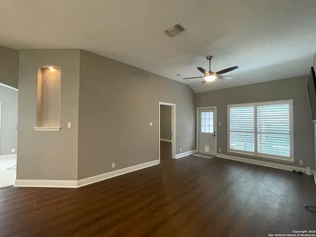 a view of an empty room with wooden floor and a window