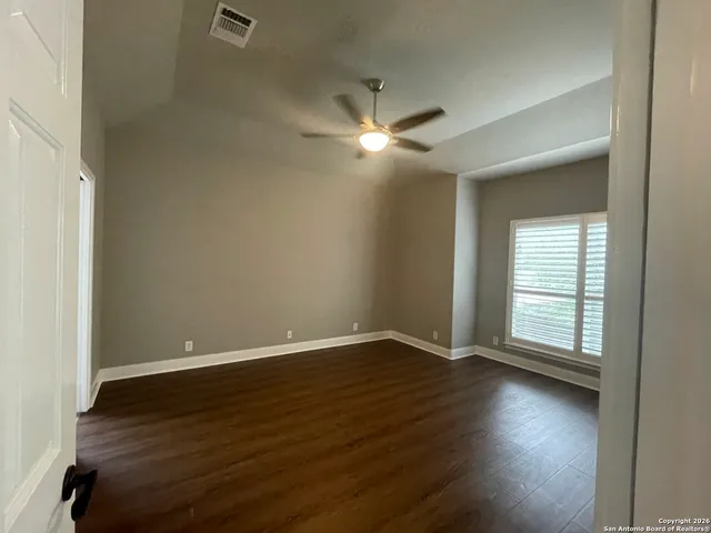a view of empty room with wooden floor and fan