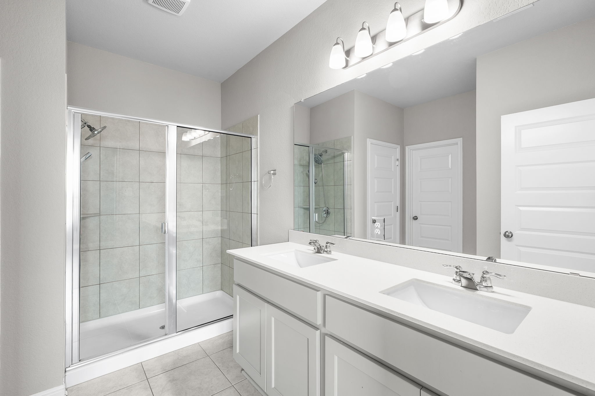 313 Mclintock Road Jarrell, TX 76537 - Photo 25 of 40 A well-lit bathroom showcases a dual vanity with a large mirror and a pristine glass-enclosed shower.