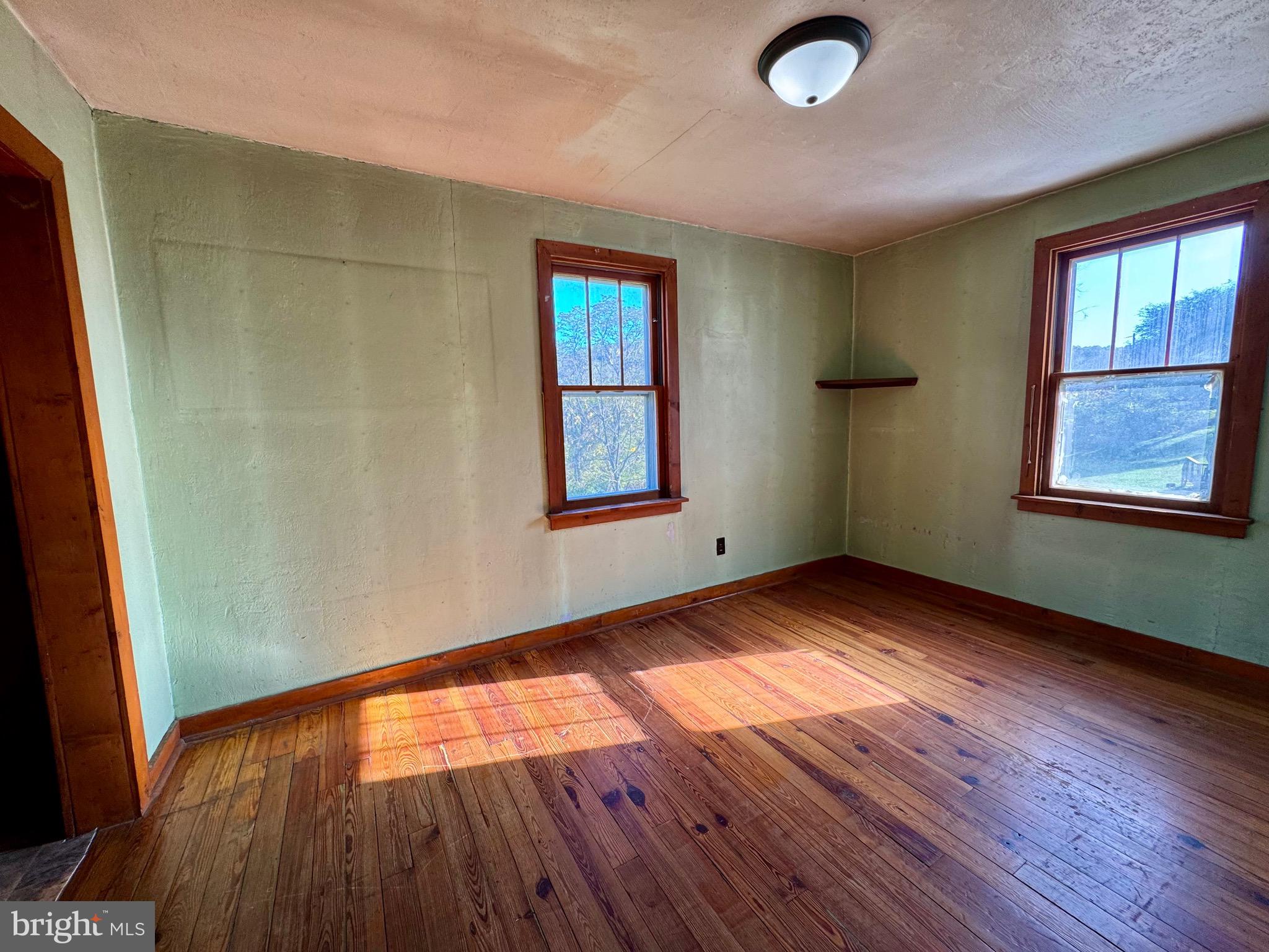 830 Harrison Avenue Berkeley Springs, WV 25411 - Photo 22 of 41 an empty room with wooden floor and windows