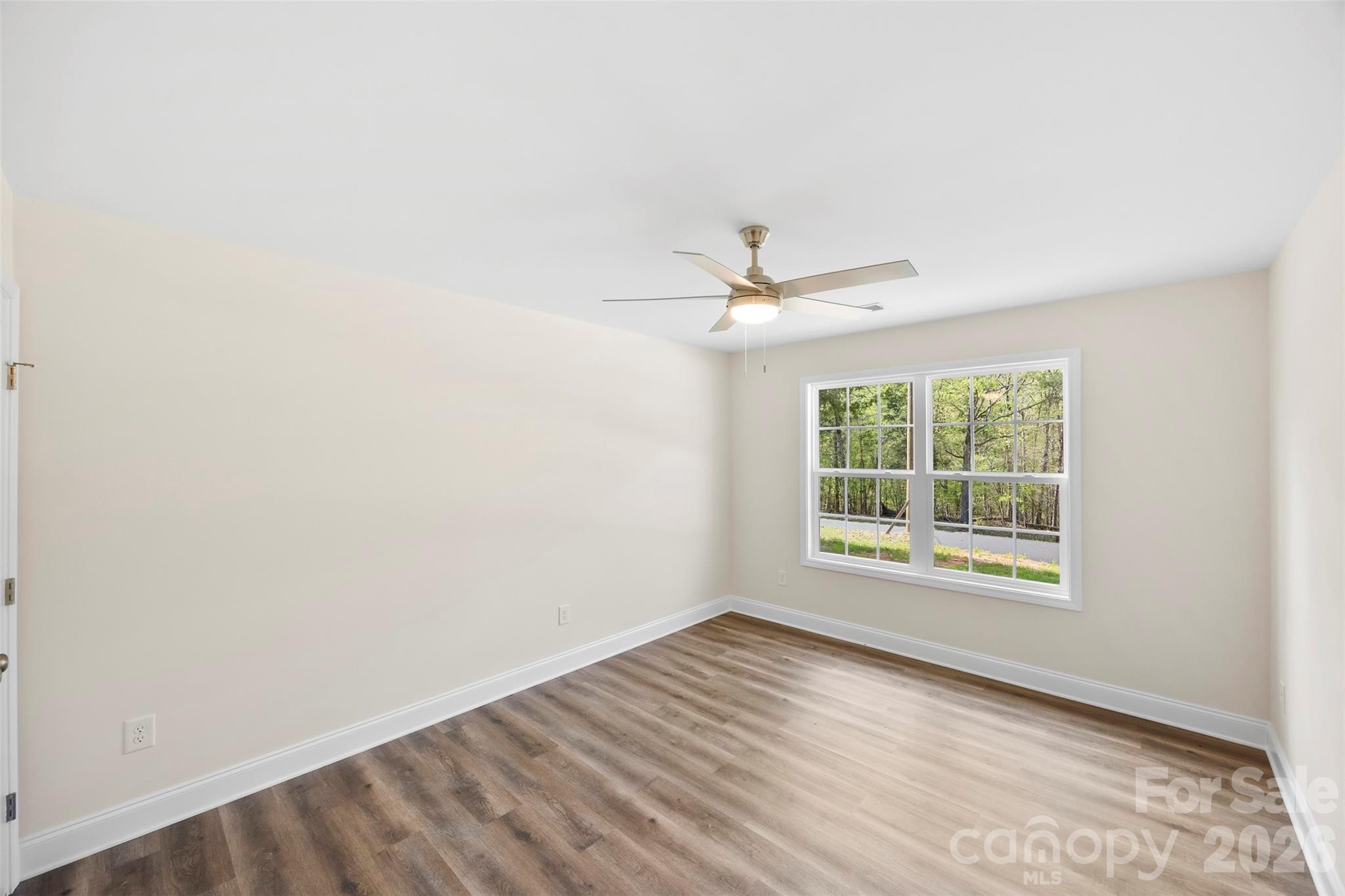 872 Roxboro Drive Mount Gilead, NC 27306 - Photo 21 of 41 an empty room with wooden floor chandelier fan and windows