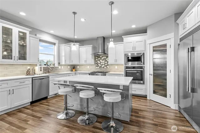 a kitchen with kitchen island granite countertop a sink a center island stainless steel appliances and cabinets
