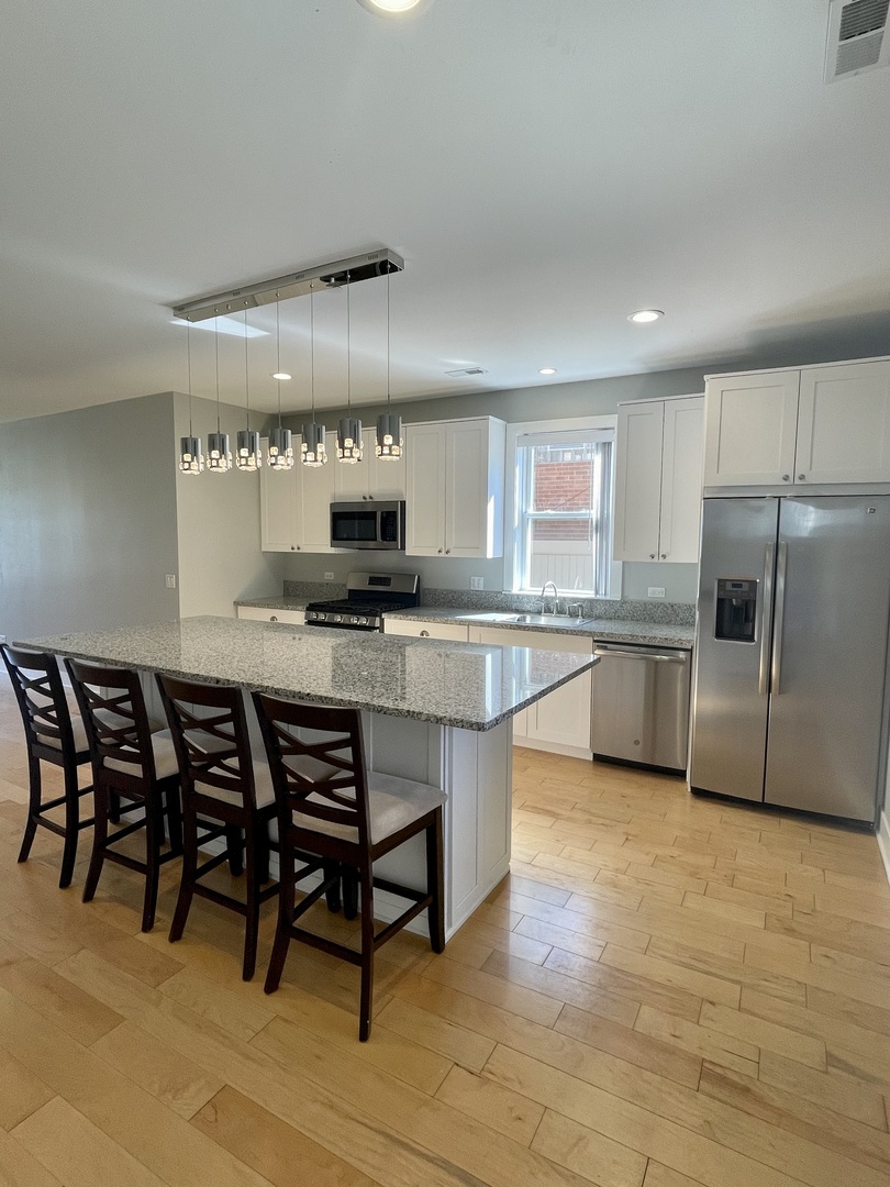 1986 Pine Street, Unit 1 Des Plaines, IL 60018 - Photo 5 of 11 a kitchen with stainless steel appliances granite countertop a sink a stove a table and chairs