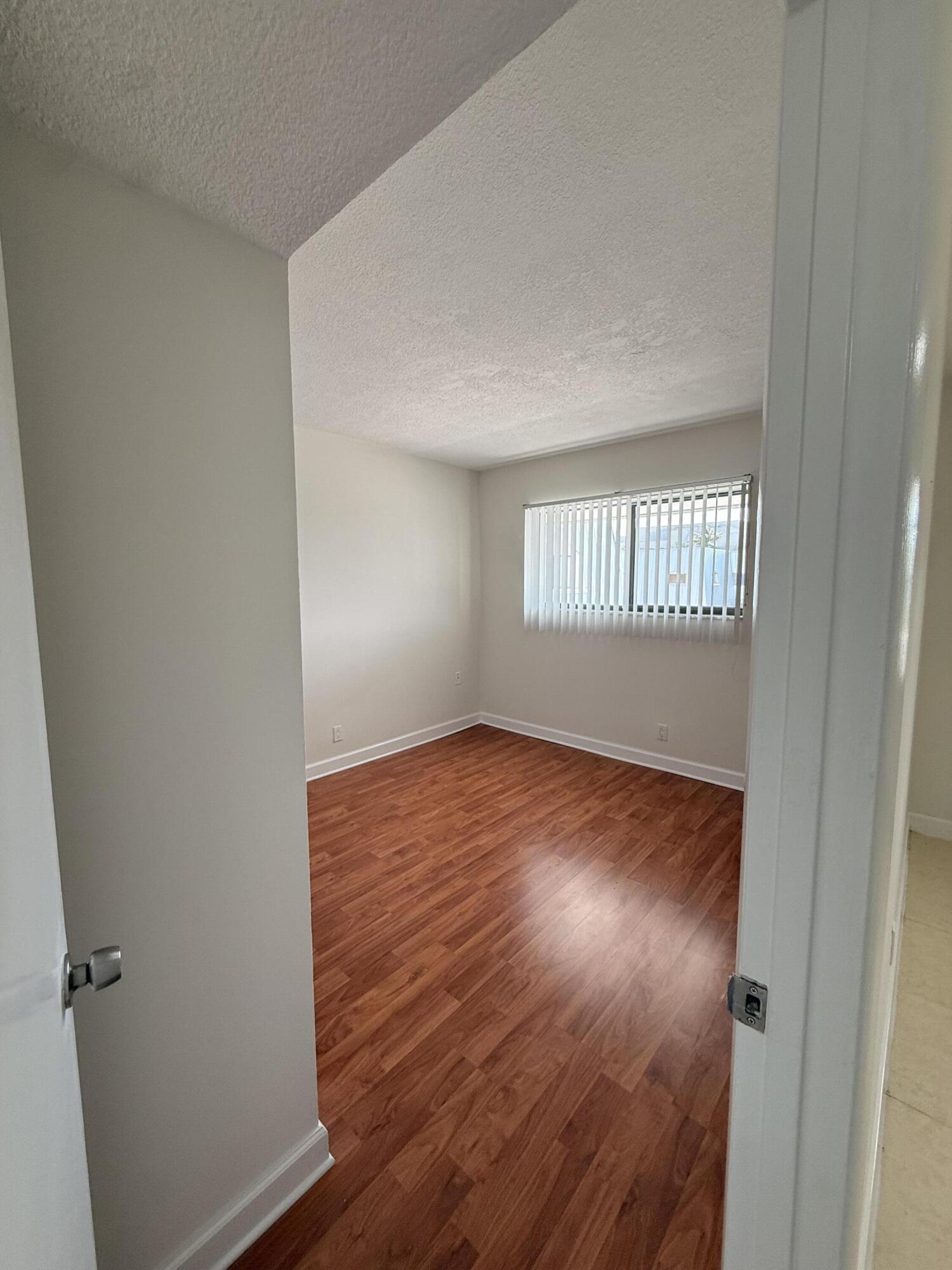 875 Northwest 13th Street, Unit 405 Boca Raton, FL 33486 - Photo 10 of 16 an empty room with wooden floor and windows