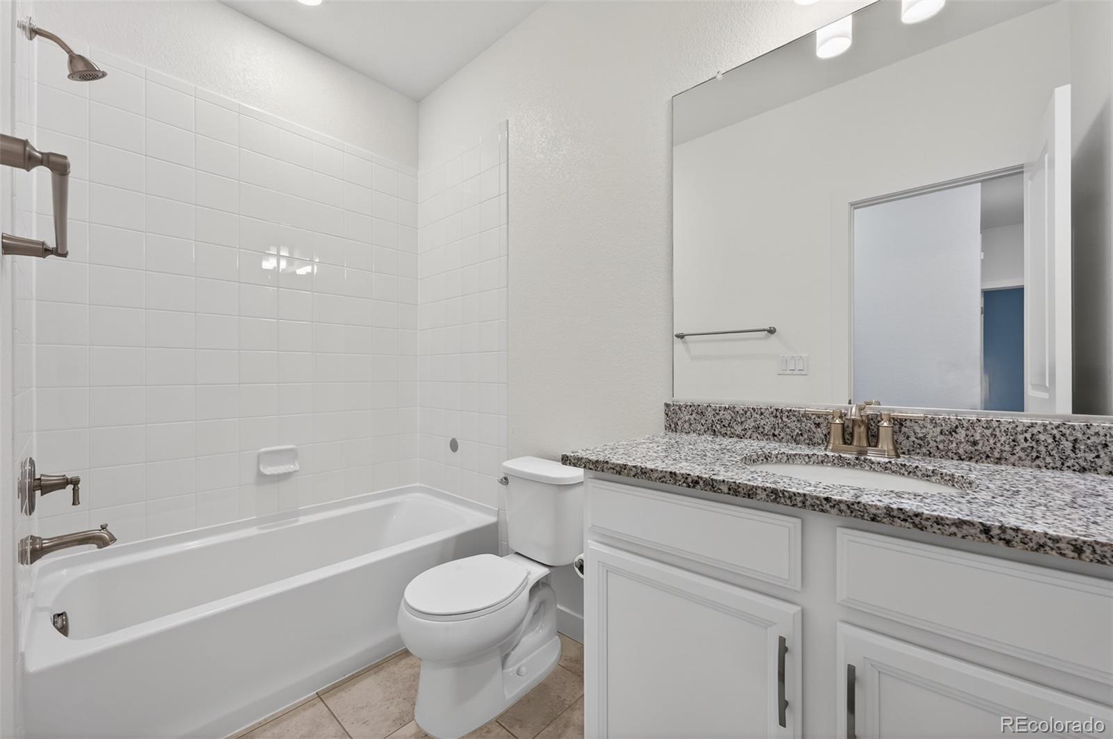6311 Stable View Street Castle Pines, CO 80108 - Photo 25 of 46 a bathroom with a granite countertop sink a toilet and bathtub