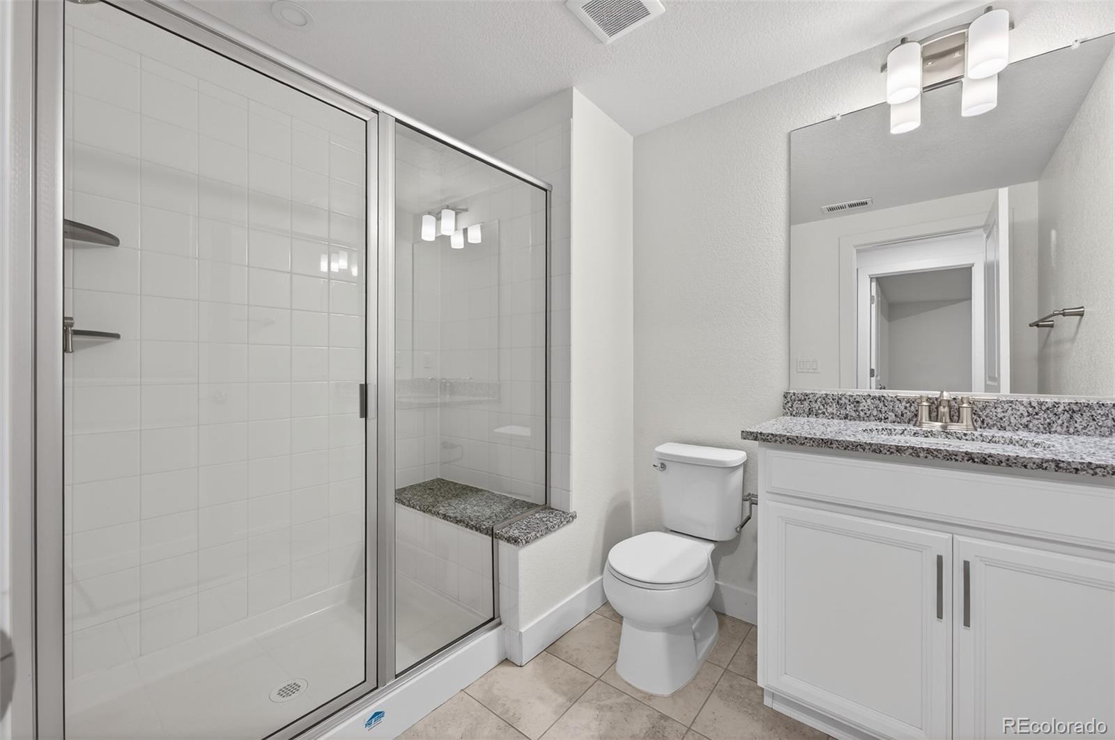6311 Stable View Street Castle Pines, CO 80108 - Photo 33 of 46 a bathroom with a granite countertop toilet a sink and a mirror