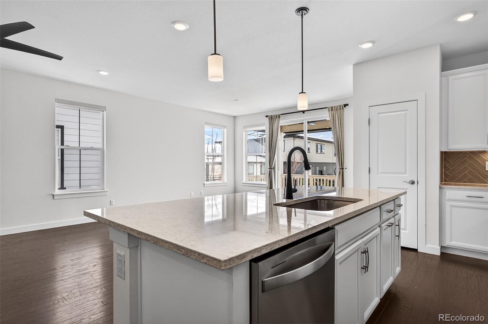 6311 Stable View Street Castle Pines, CO 80108 - Photo 10 of 46 a kitchen with stainless steel appliances granite countertop a sink a oven and a dining table with wooden floor