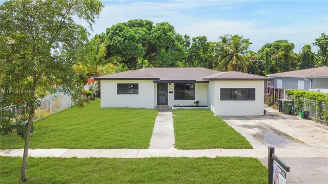 a front view of a house with a yard and trees