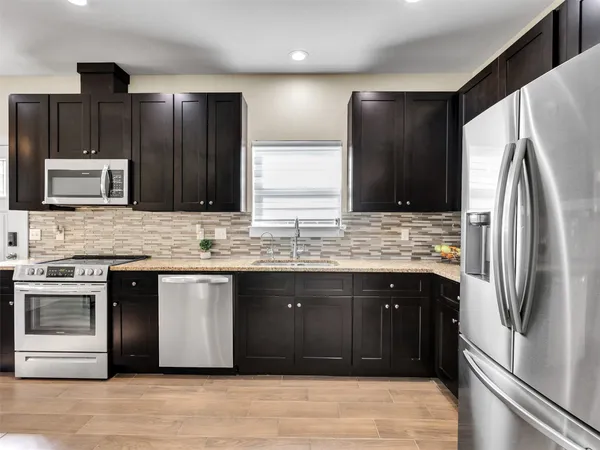 a kitchen with stainless steel appliances granite countertop a refrigerator and a sink