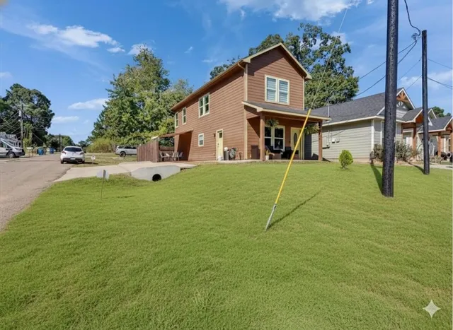 a view of a white house with a big yard and potted plants