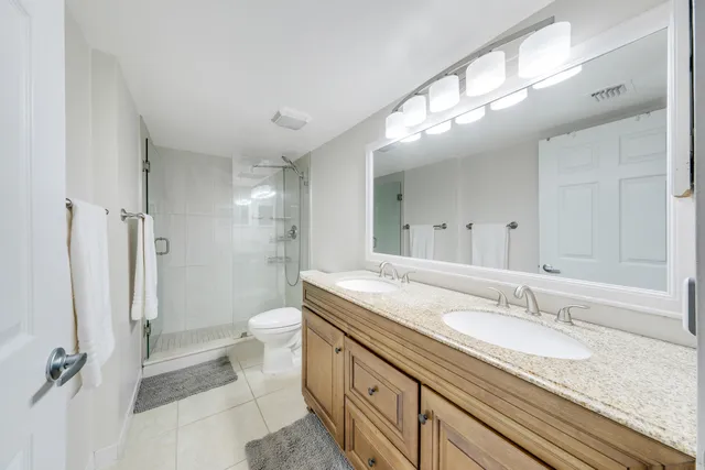 a bathroom with a granite countertop sink a toilet a mirror and shower