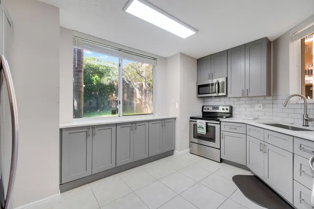 a kitchen with white cabinets appliances a sink and a window