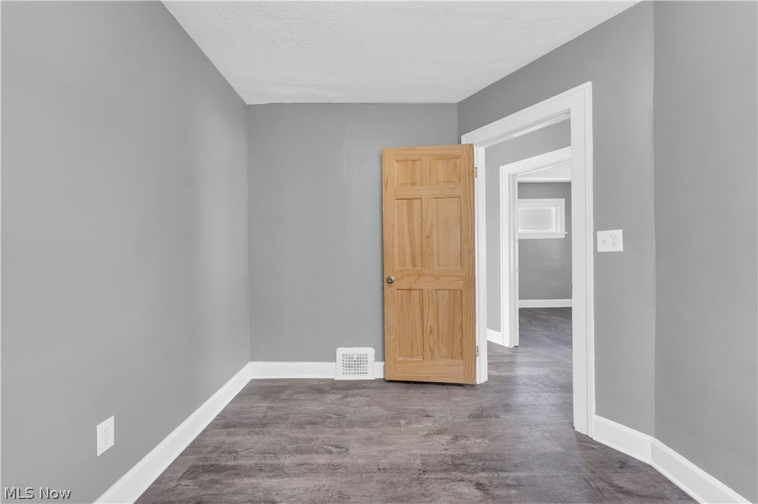 12808 Havana Road Cleveland, OH 44125 - Photo 11 of 19 Room featuring wood-finish flooring, light gray walls, white trim, and a natural wood six-panel door