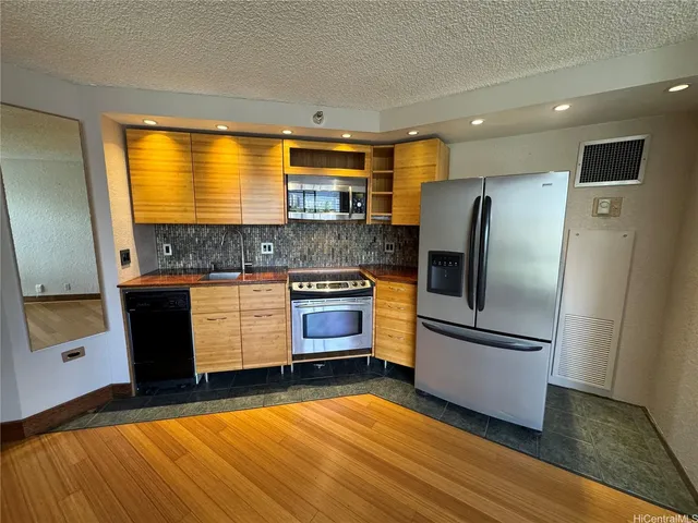 a kitchen with stainless steel appliances granite countertop a refrigerator a stove and a sink