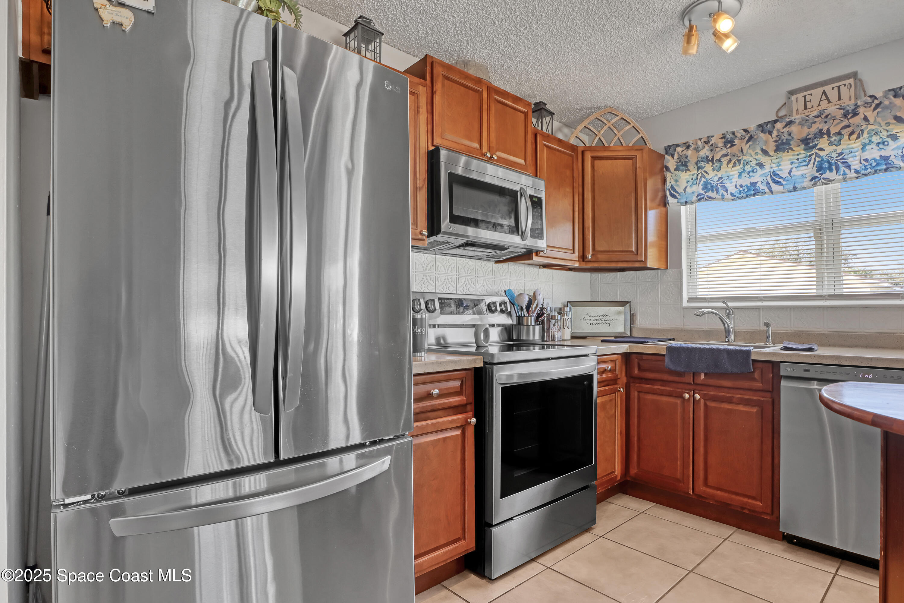 1513 Creel Road Northeast Palm Bay, FL 32905 - Photo 11 of 31 a kitchen with stainless steel appliances granite countertop a refrigerator stove a sink and dishwasher with wooden floor