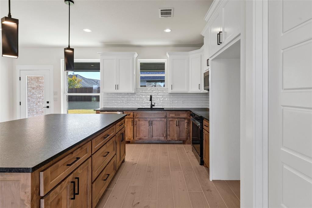 3306 Promenade Court Granbury, TX 76049 - Photo 11 of 40 a kitchen with stainless steel appliances granite countertop a sink a stove and a refrigerator