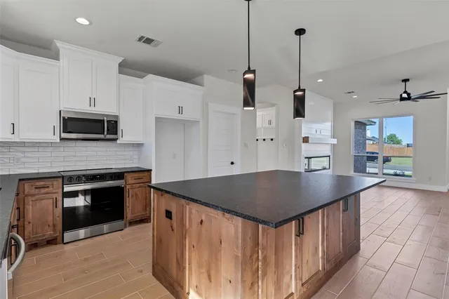 a kitchen with stainless steel appliances kitchen island a stove a sink a kitchen island a stove a refrigerator a dining table and chairs