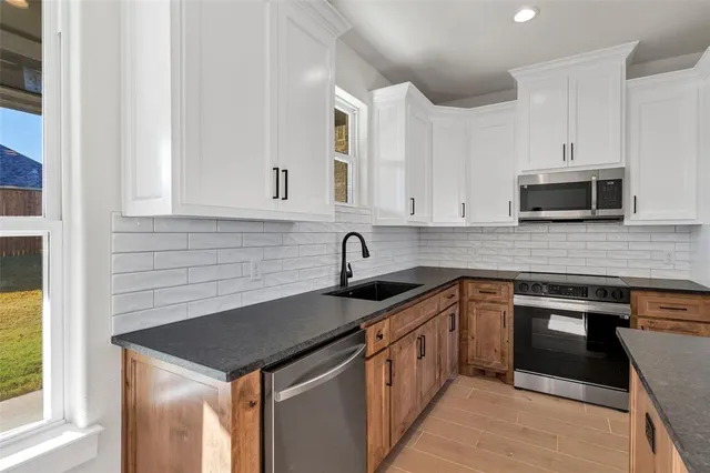 a kitchen with stainless steel appliances granite countertop a sink stove and microwave