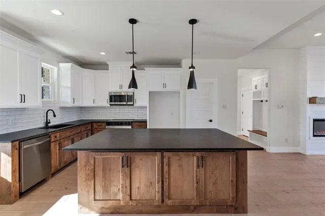 a kitchen with stainless steel appliances granite countertop a sink a stove and a wooden floors