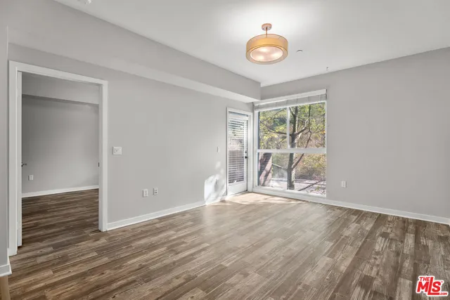 a view of an empty room with wooden floor and a window