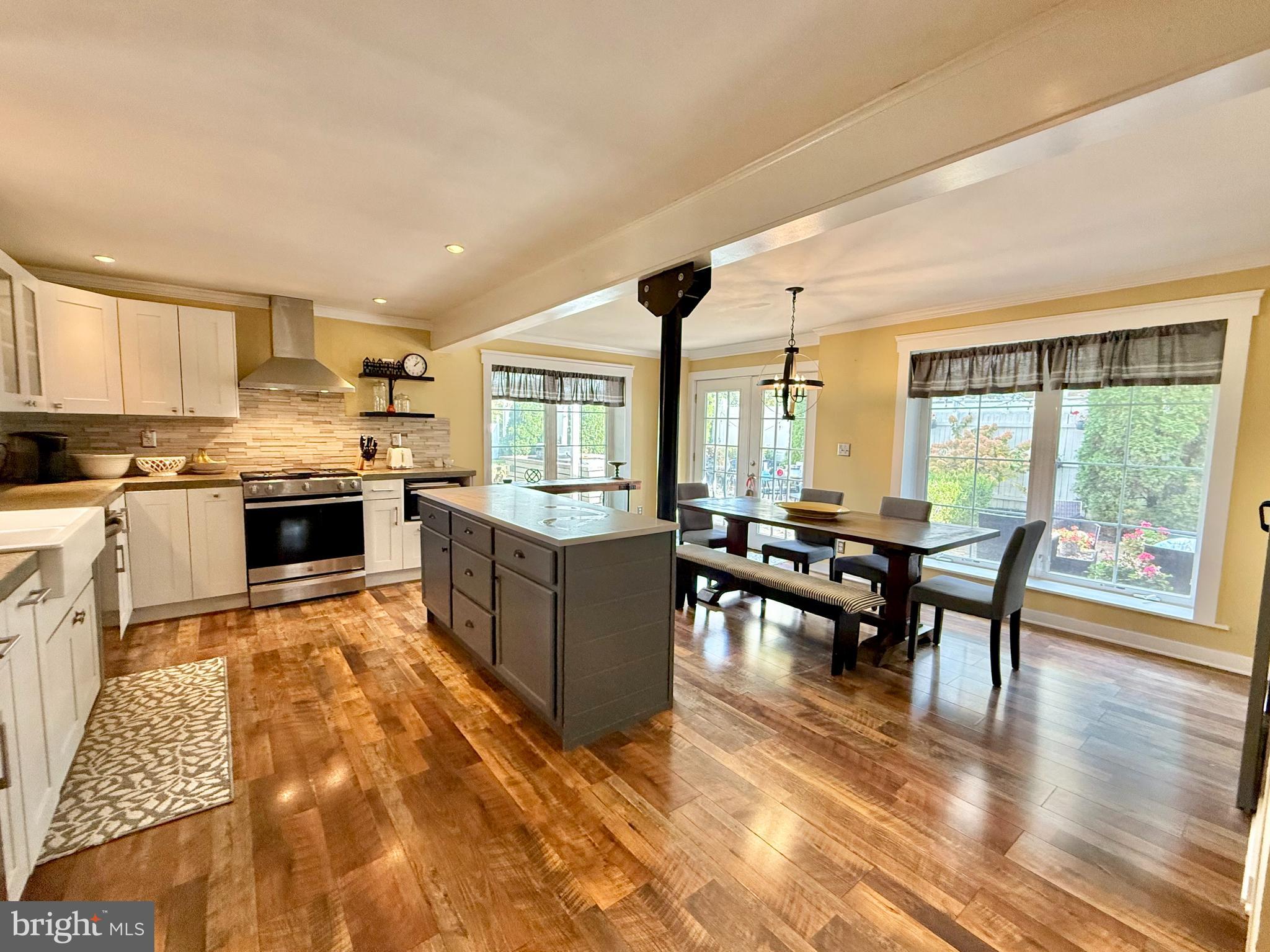 1303 Bruce Road Oreland, PA 19075 - Photo 4 of 13 a kitchen with stainless steel appliances kitchen island granite countertop a stove top oven a sink a dining table and chairs with wooden floor