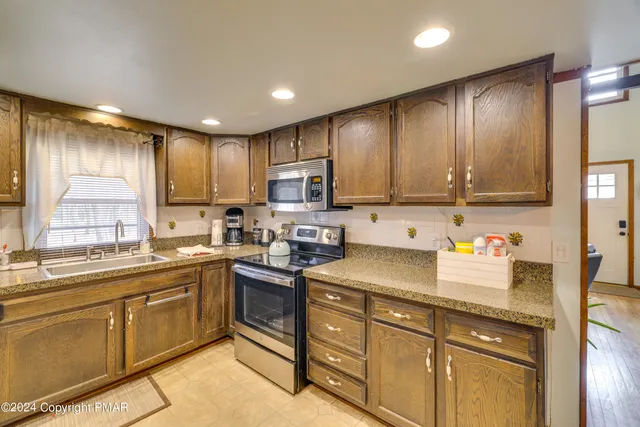 a kitchen with stainless steel appliances granite countertop table chairs and a refrigerator
