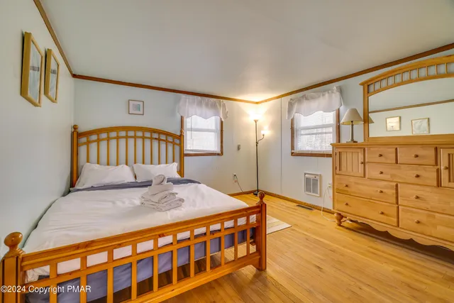 a spacious bedroom with a bed and wooden floor