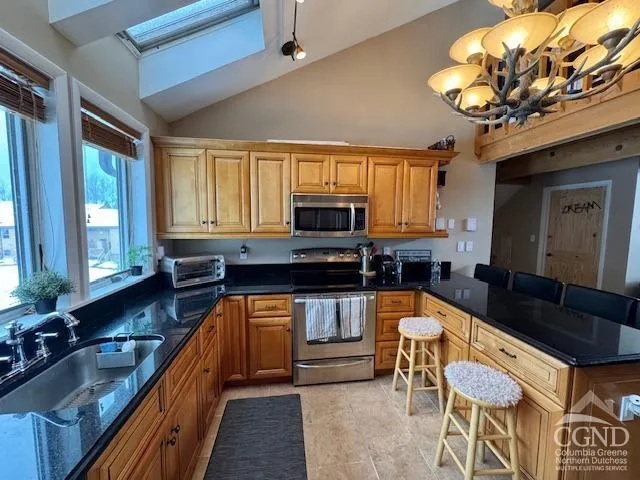 a kitchen with stainless steel appliances granite countertop a refrigerator a stove and a sink with wooden floor