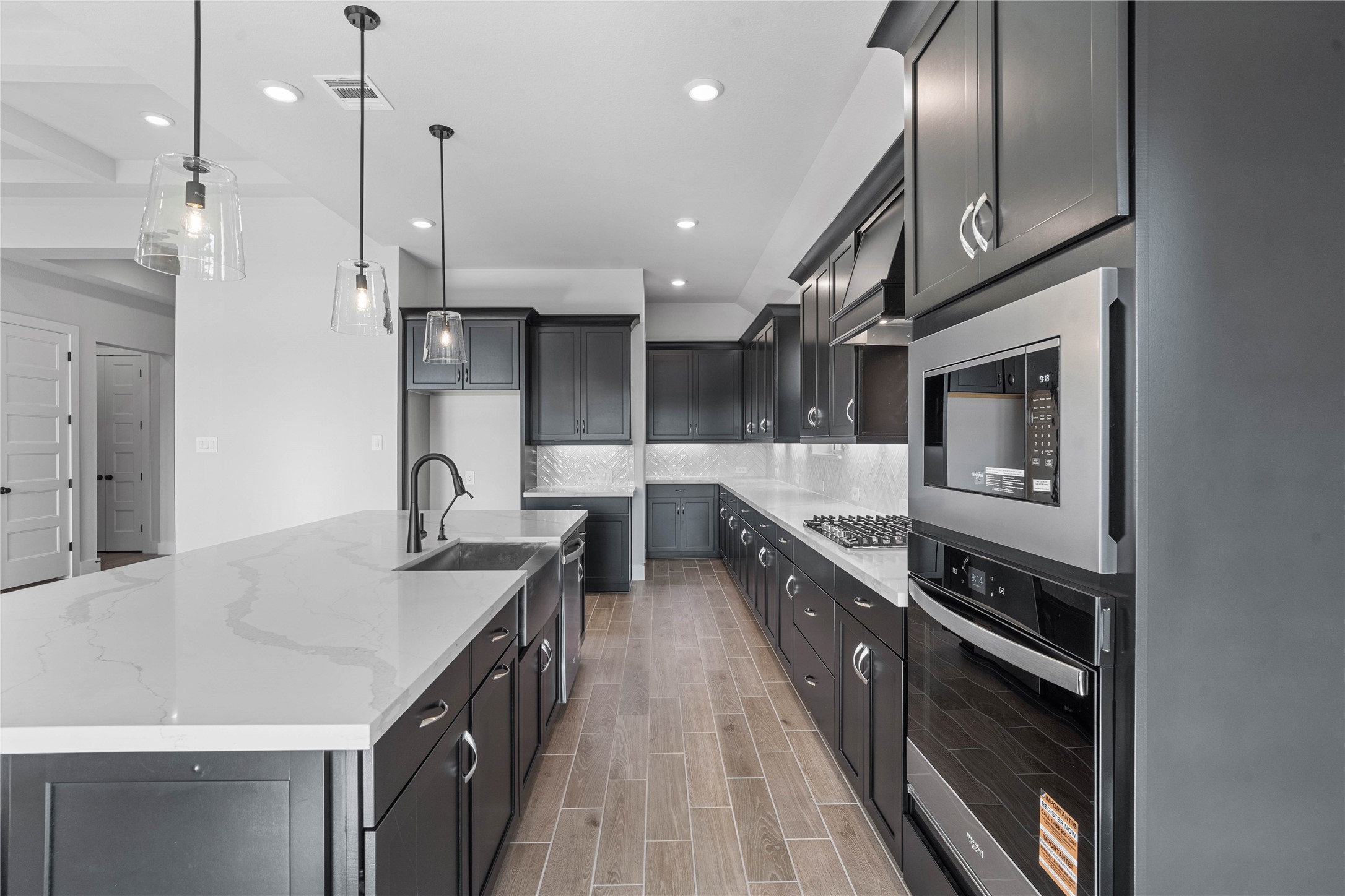 2114 Rowl Street Montgomery, TX 77316 - Photo 26 of 50 This gourmet kitchen is a true entertainer's dream, featuring sleek, modern design elements like the expansive white quartz island and dark cabinetry. Top-of-the-line appliances and elegant pendant lighting create a clean, bright, and inviting space perfect for both casual dining and hosting sophisticated gatherings.