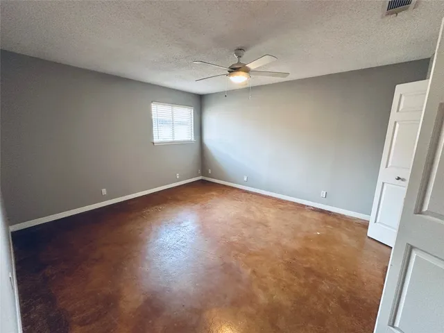 an empty room with a chandelier fan and windows