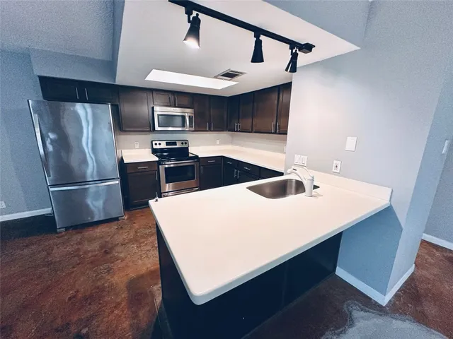 a kitchen with stainless steel appliances a sink a stove a refrigerator and cabinets