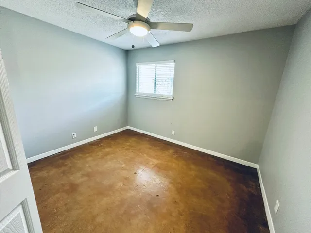 an empty room with a window and a fan