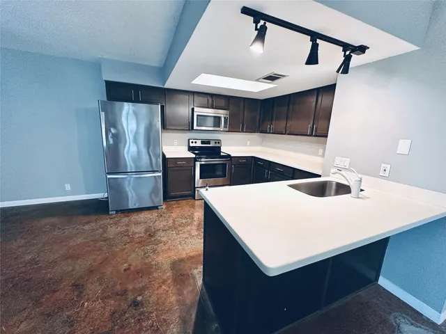 a kitchen with a sink a refrigerator and cabinets