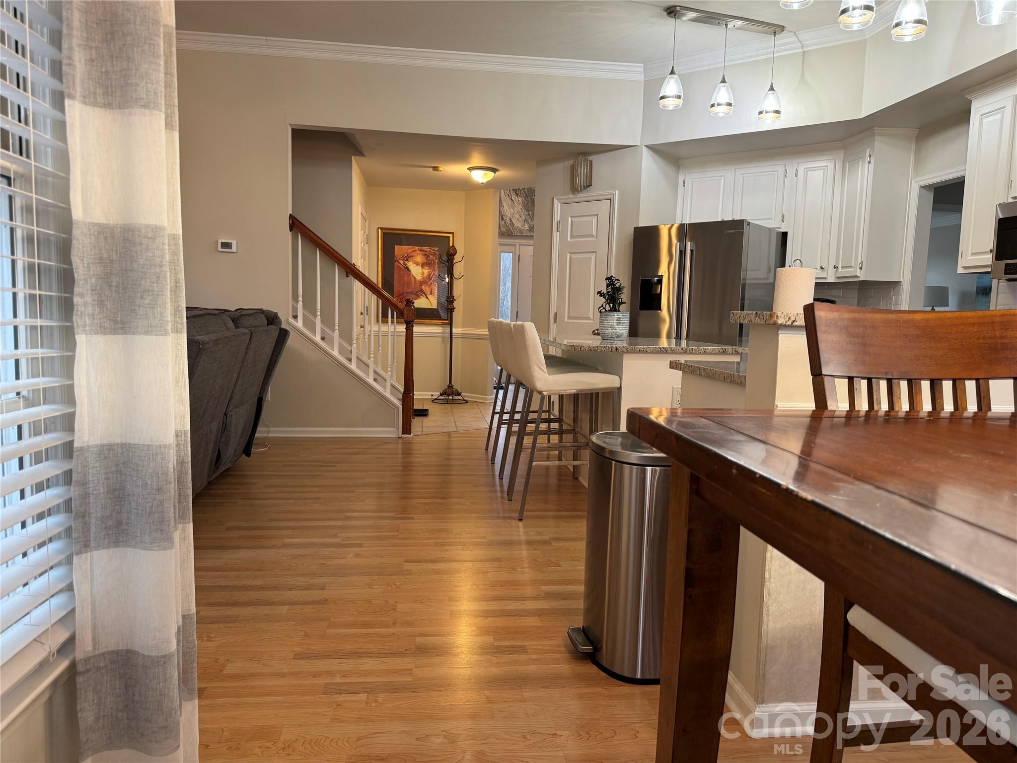 4846 Fortunes Ridge Trail Charlotte, NC 28269 - Photo 13 of 43 a dining hall with stainless steel appliances kitchen island granite countertop a refrigerator a stove a microwave oven with white cabinets and wooden floor