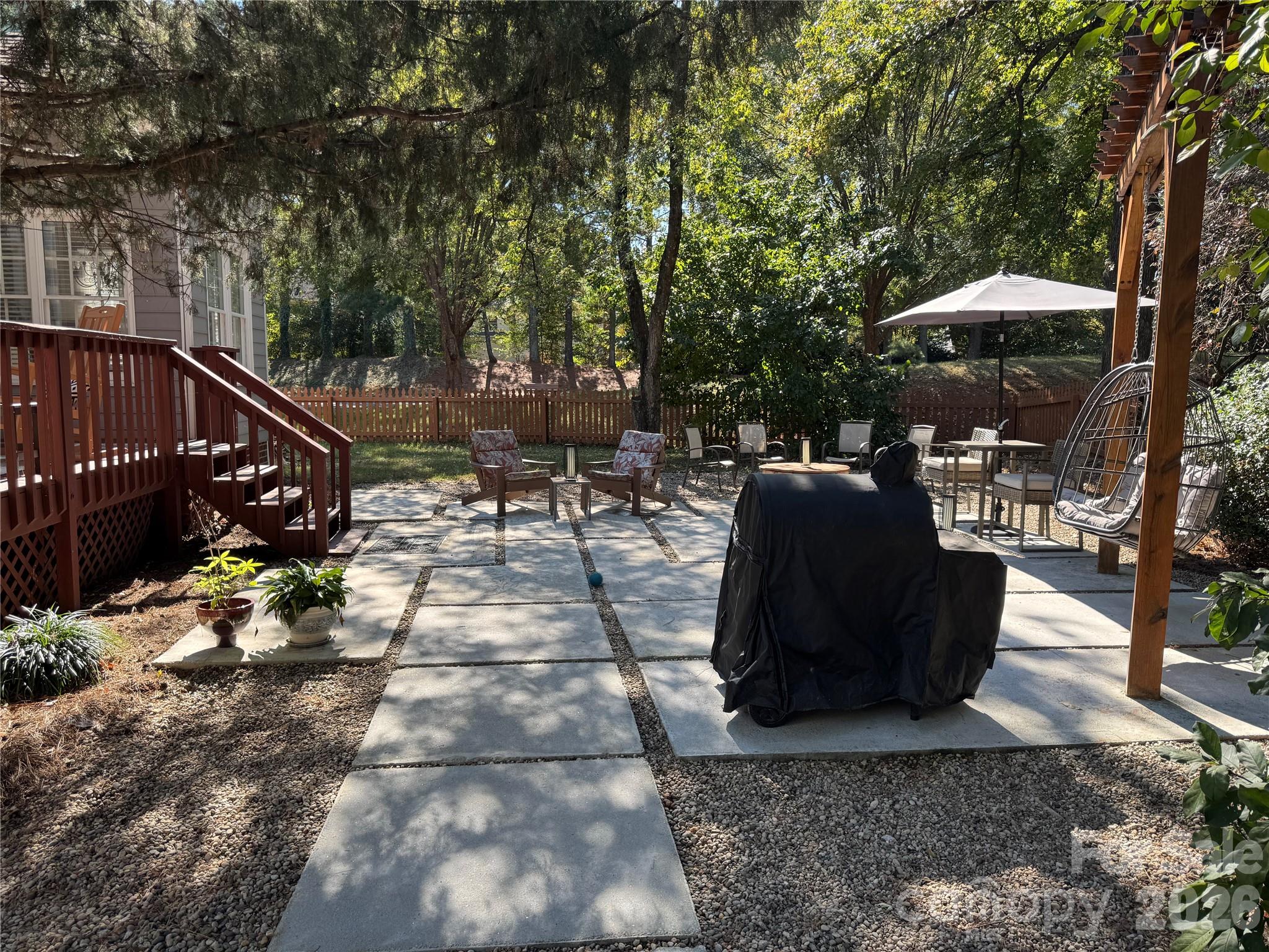 4846 Fortunes Ridge Trail Charlotte, NC 28269 - Photo 38 of 43 a view of a patio with table and chairs under an umbrella with large trees