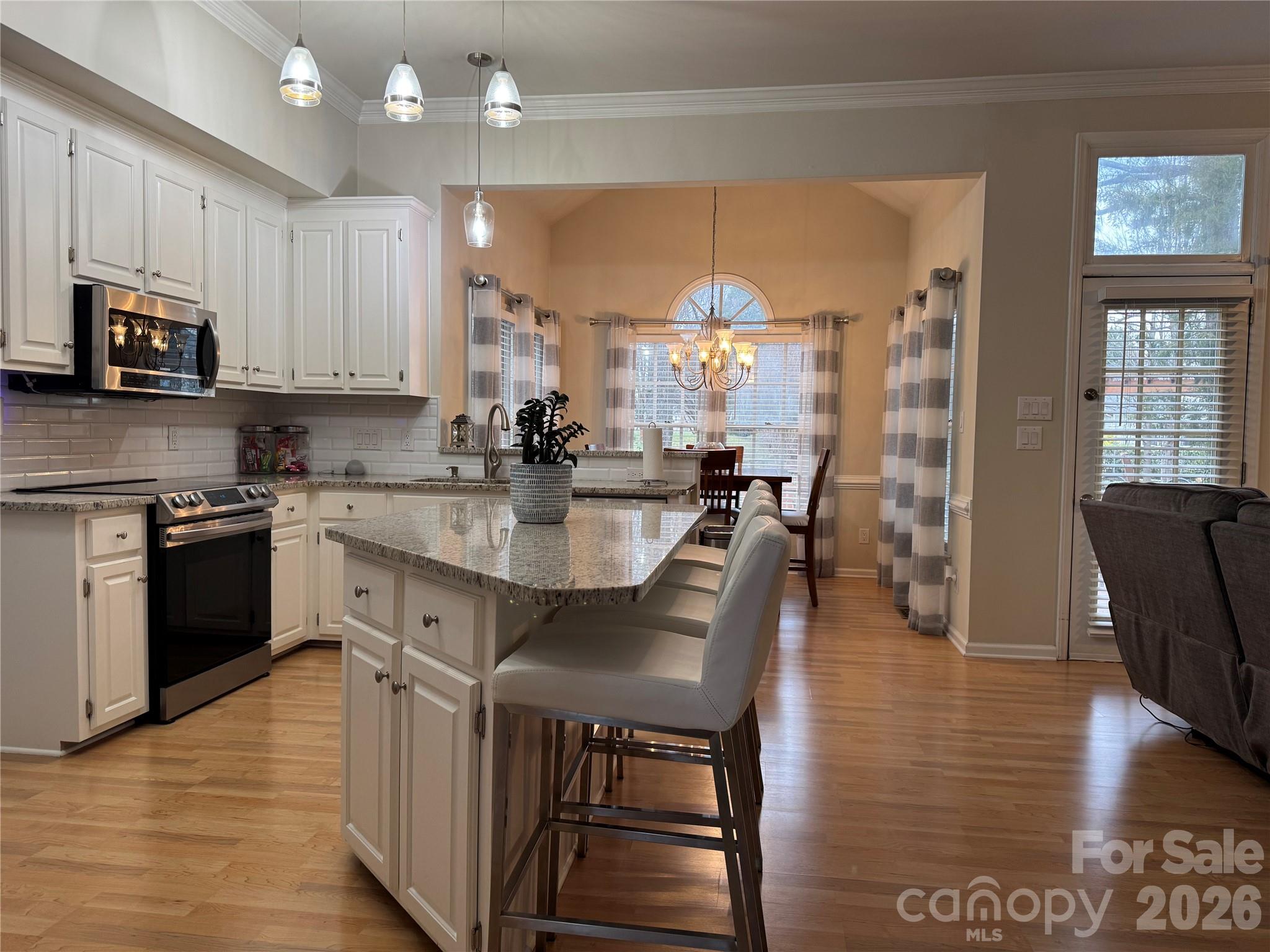 4846 Fortunes Ridge Trail Charlotte, NC 28269 - Photo 4 of 43 a kitchen with stainless steel appliances granite countertop a stove top oven a sink dishwasher a dining table and chairs with wooden floor