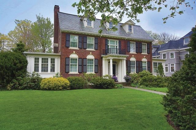 a front view of a house with a yard and trees