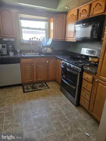 a kitchen with kitchen island granite countertop a stove a sink and a microwave