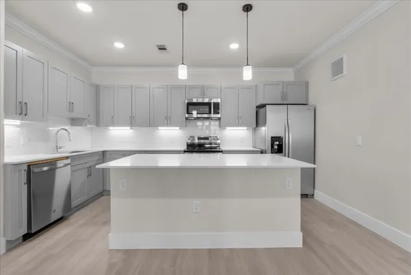 a kitchen with a refrigerator a sink and wooden floor