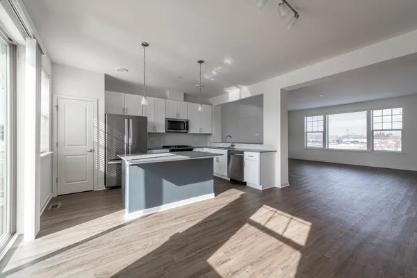 a kitchen with granite countertop a refrigerator a sink dishwasher a stove and white cabinets with wooden floor