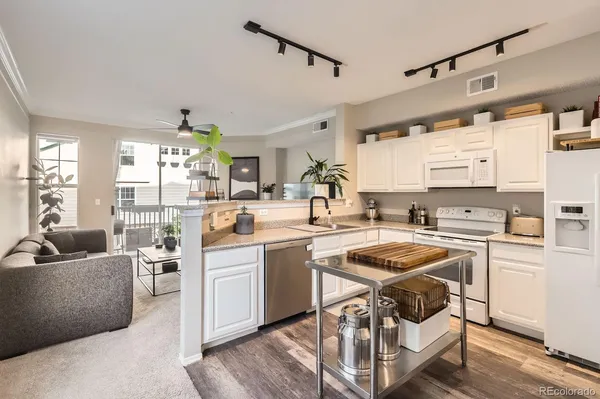 a kitchen with stainless steel appliances a stove a sink dishwasher and white cabinets with wooden floor