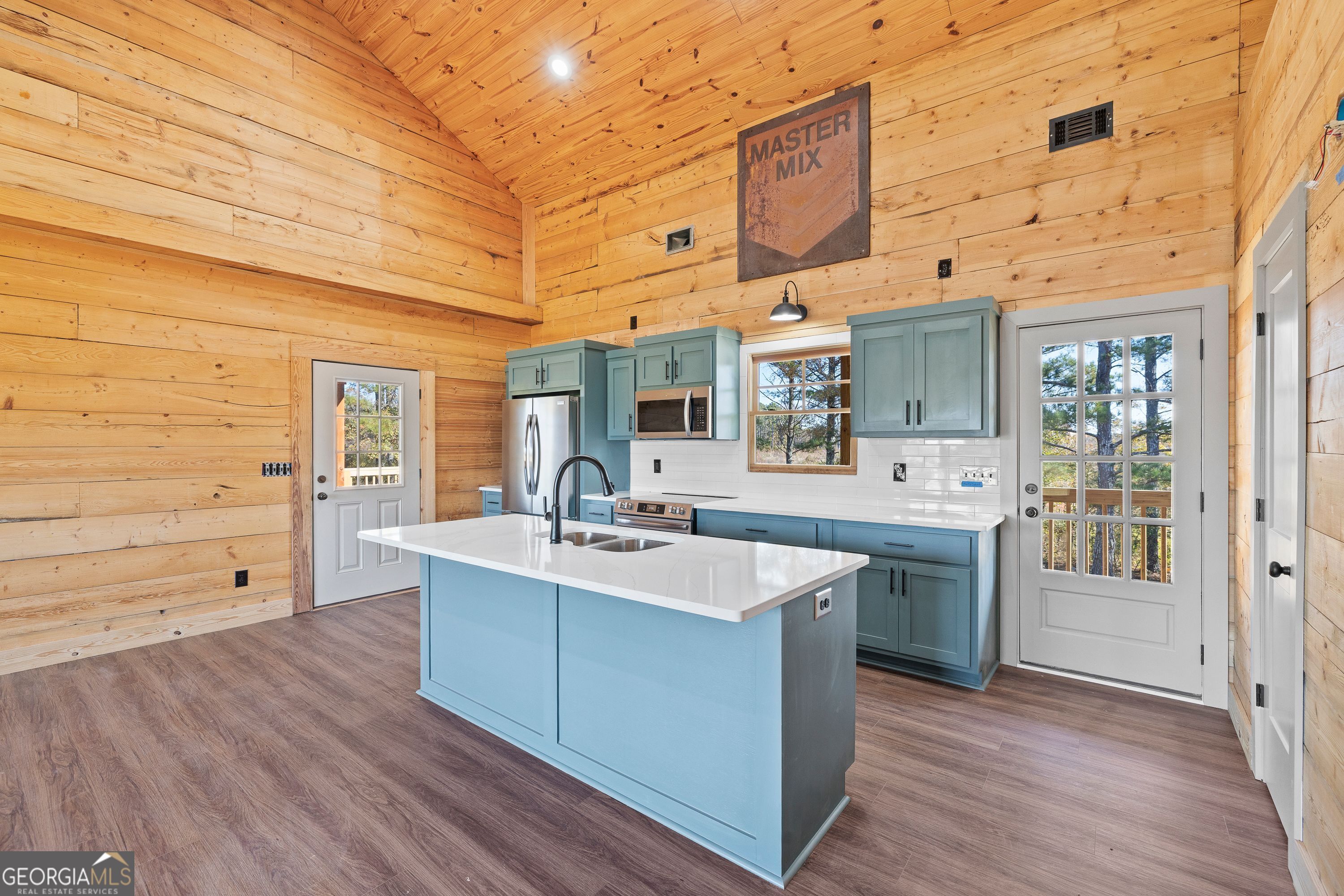 130 North Wesley Chapel Road Eatonton, GA 31024 - Photo 22 of 45 a large white kitchen with wooden floor and stainless steel appliances