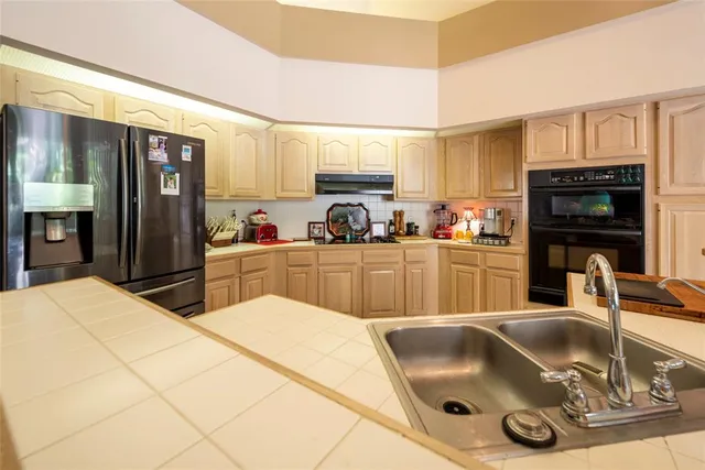 a kitchen with stainless steel appliances granite countertop a refrigerator and a stove top oven