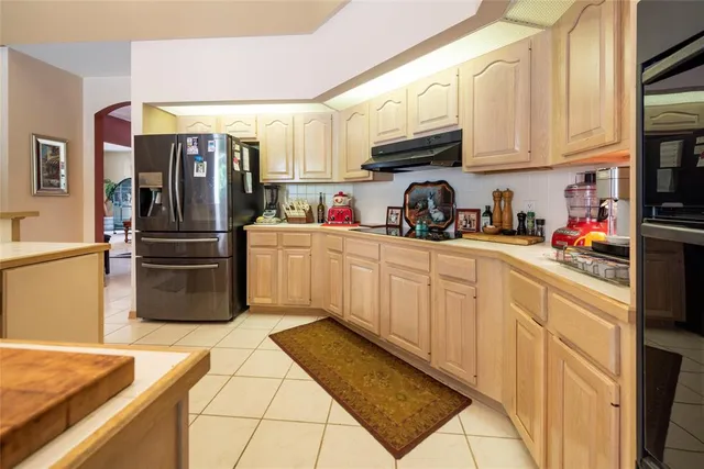 a dining room with stainless steel appliances a table chairs and a refrigerator