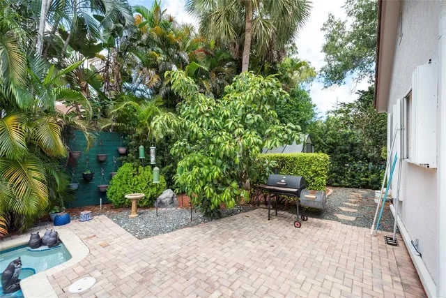 a view of a small yard in front of a house with a large tree and wooden fence
